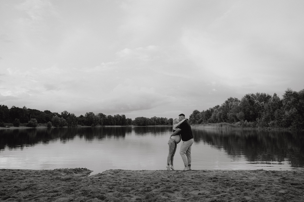 Babybauchfotos in berlin mit der Berliner Fotografin für Kinderfotografie Maria Brussig Lensofbeauty. fotos am See. Fotoshooting Babybauch im grünen. Wasser im Hintergrund. Paarfotos zusammen am See.