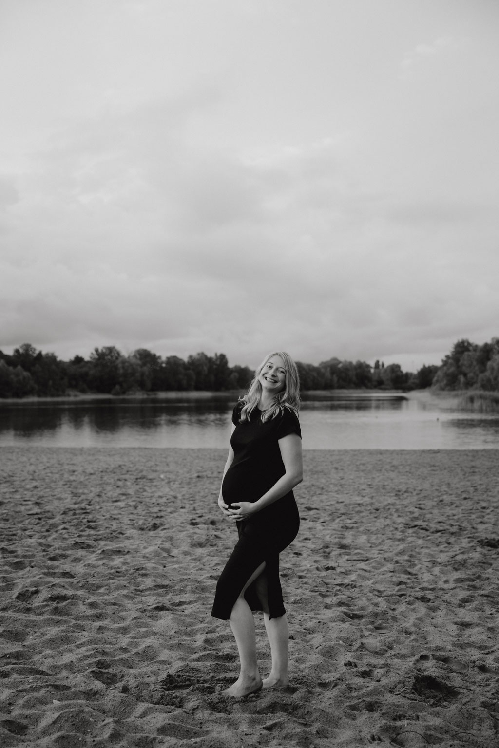 Babybauchfotos in berlin mit der Berliner Fotografin für Kinderfotografie Maria Brussig Lensofbeauty. fotos am See. Fotoshooting Babybauch im grünen. Wasser im Hintergrund. Paarfotos zusammen am See.