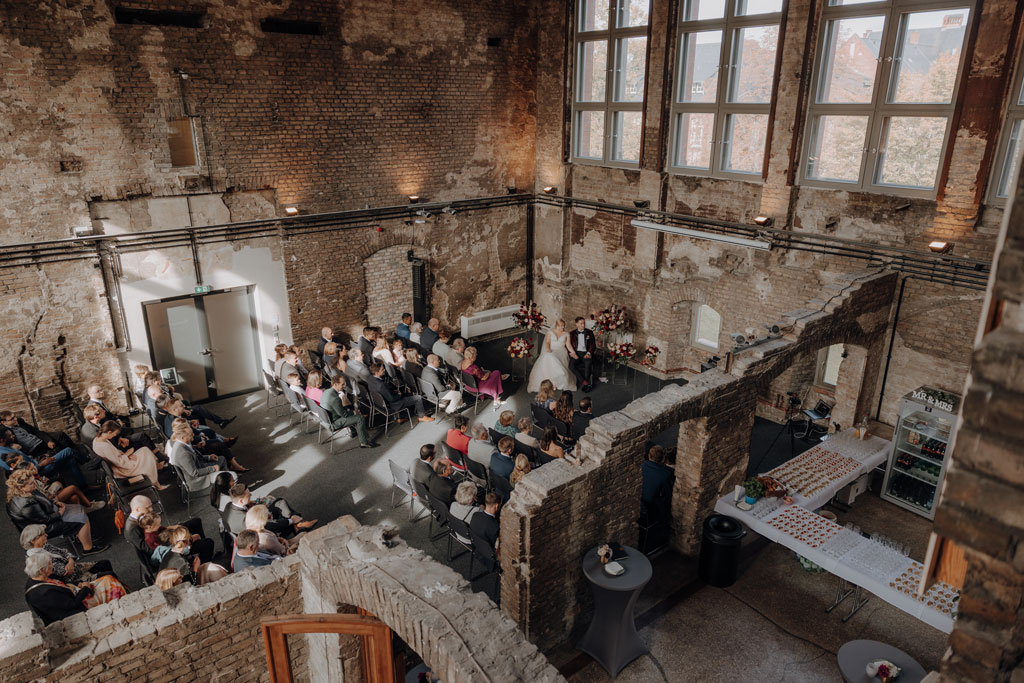 trauung Inder charité in der hoersaalruine mit mir als hochzeitsfotograf und roten tollen Blumen in berlin in einer tollen hochzeitsloaction