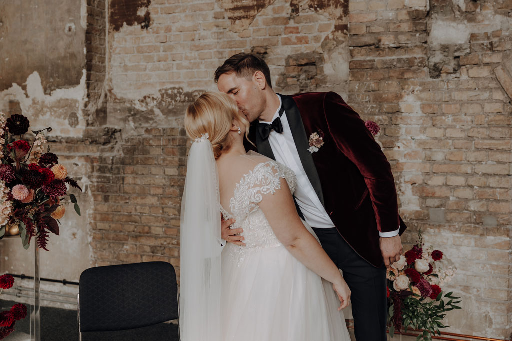 trauung Inder charité in der hoersaalruine mit mir als hochzeitsfotograf und roten tollen Blumen in berlin in einer tollen hochzeitsloaction