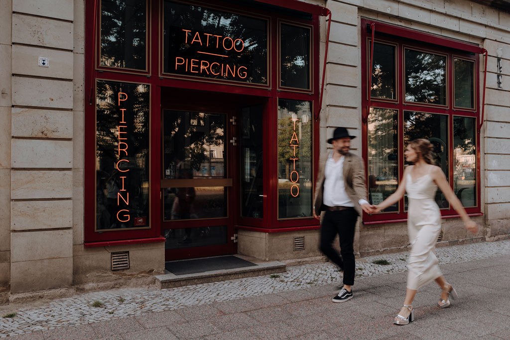 Hochzeit in berlin an der Frankfurter Allee mit Fernsehturm im Hintergrund und Tattoo und Piercing studio. Eheringe auf pizza. Paarfotos in berlin. Hochzeit mitten in berlin. außergewöhnliche Festival rock Hochzeit. Festival Hochzeit. rock Hochzeit.