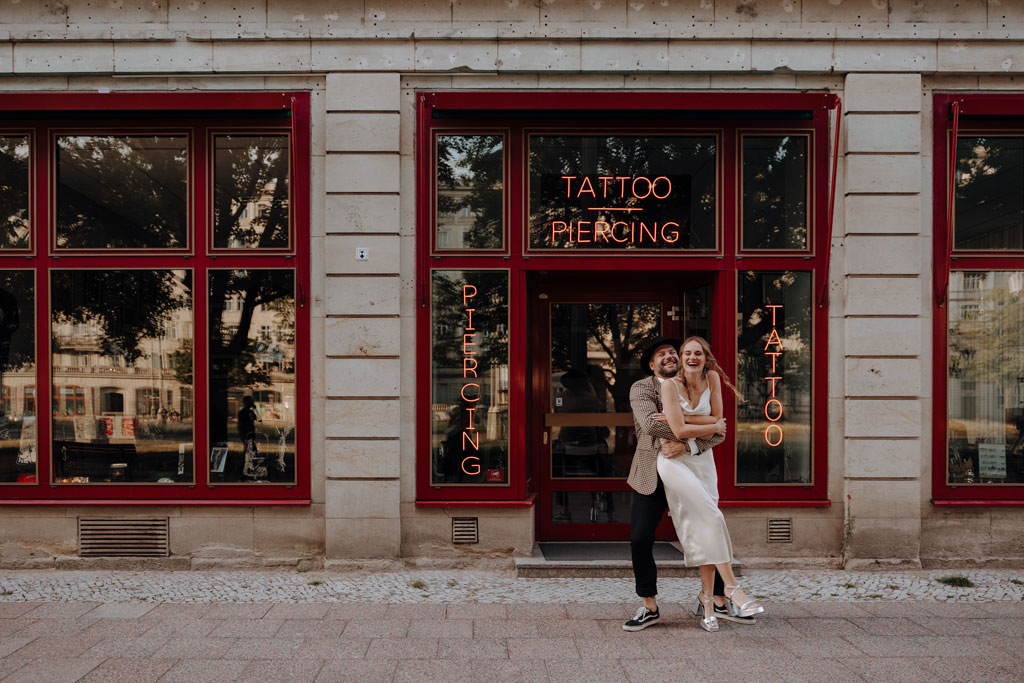 Hochzeit in berlin an der Frankfurter Allee mit Fernsehturm im Hintergrund und Tattoo und Piercing studio. Eheringe auf pizza. Paarfotos in berlin. Hochzeit mitten in berlin. außergewöhnliche Festival rock Hochzeit. Festival Hochzeit. rock Hochzeit.