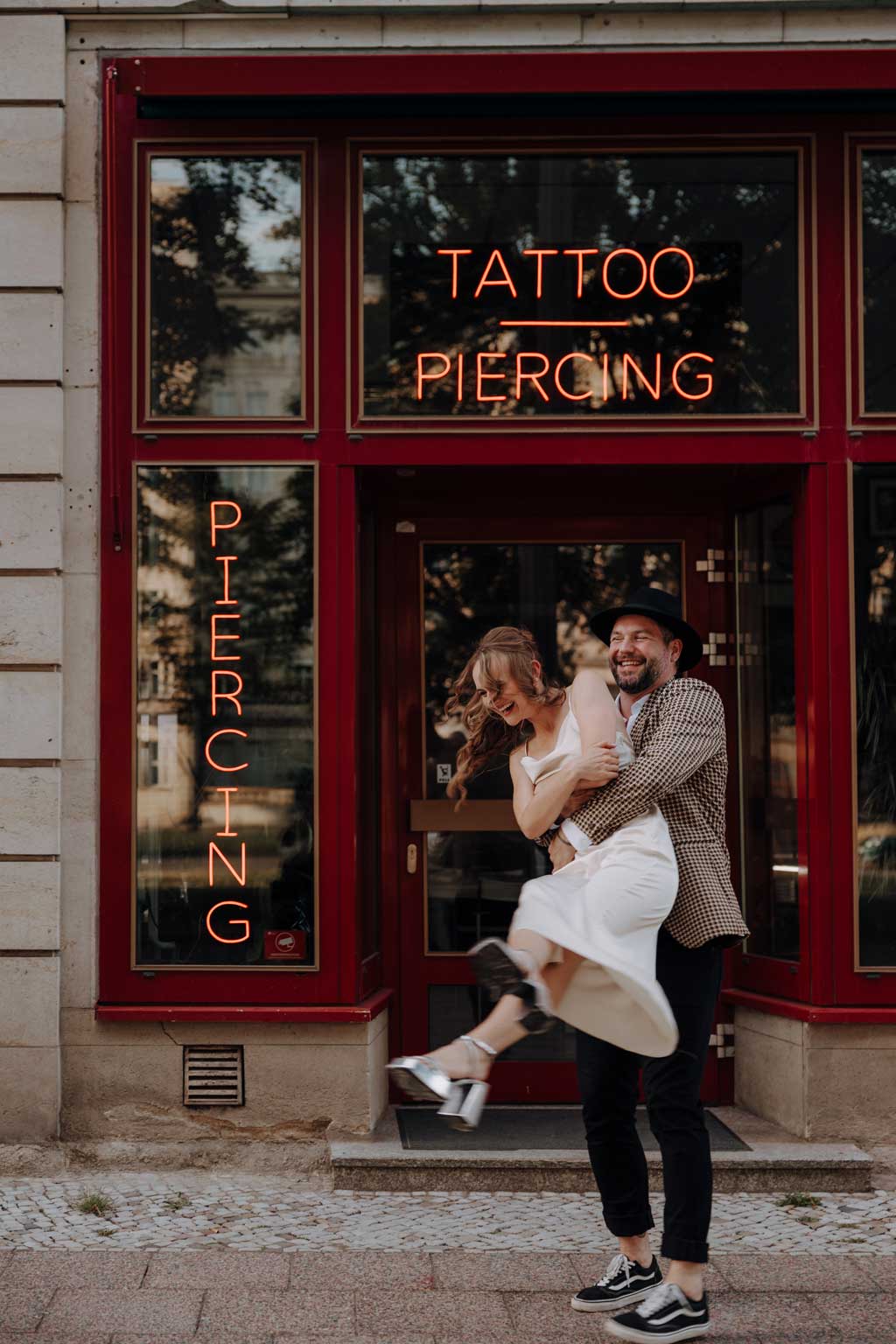 Hochzeit in berlin an der Frankfurter Allee mit Fernsehturm im Hintergrund und Tattoo und Piercing studio. Eheringe auf pizza. Paarfotos in berlin. Hochzeit mitten in berlin. außergewöhnliche Festival rock Hochzeit. Festival Hochzeit. rock Hochzeit.