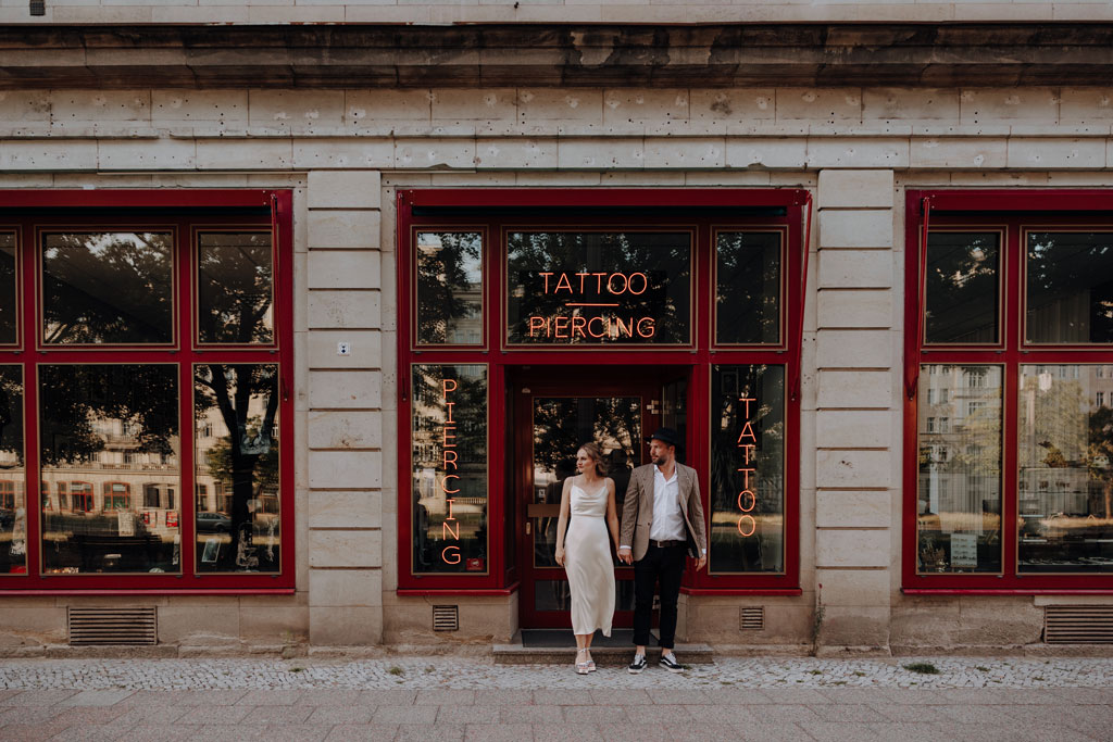 Hochzeit in berlin an der Frankfurter Allee mit Fernsehturm im Hintergrund und Tattoo und Piercing studio. Eheringe auf pizza. Paarfotos in berlin. Hochzeit mitten in berlin. außergewöhnliche Festival rock Hochzeit. Festival Hochzeit. rock Hochzeit.